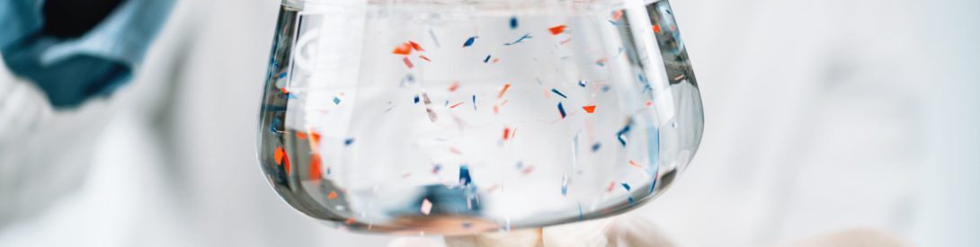 Microplastics laboratory analysis. Scientist observing microplastics or tiny plastic particles in a flask with a water sample.