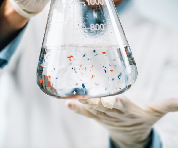 Microplastics laboratory analysis. Scientist observing microplastics or tiny plastic particles in a flask with a water sample.
